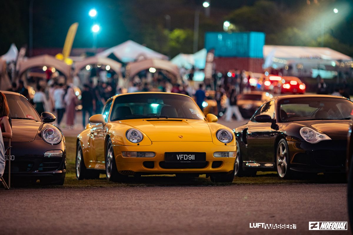 Yellow 993 flanked by two dark 911s under the night lights