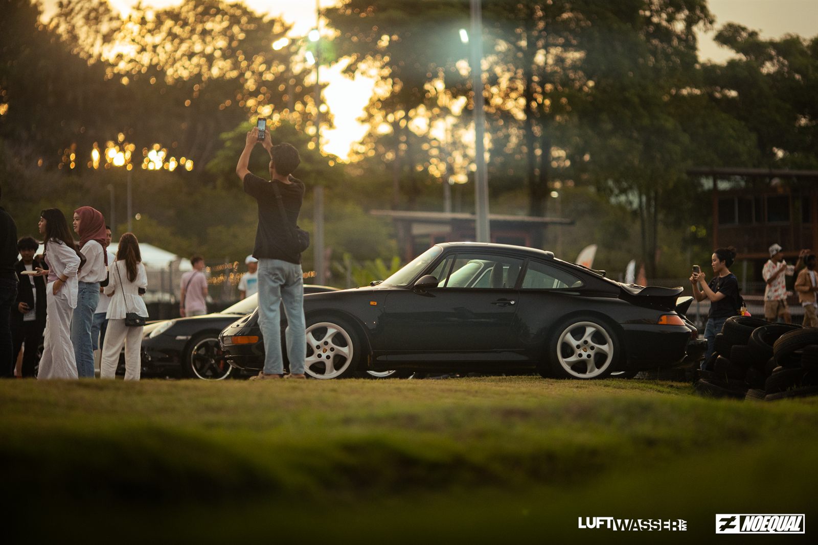 Dark green 993 in profile as the sun sets behind the trees